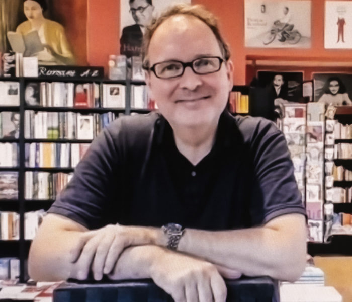 Lächelndes Bild von Klaus Kowalke vor einem Bücherregal.